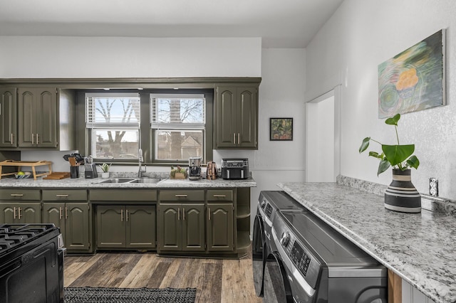 kitchen featuring dark hardwood / wood-style flooring, sink, washer / dryer, and gas stove