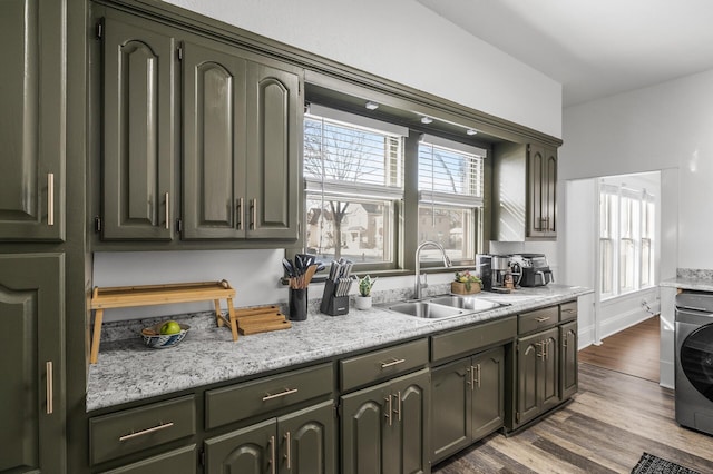 kitchen with washer / dryer, sink, and dark hardwood / wood-style floors