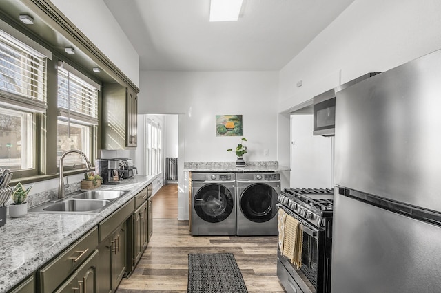 laundry area with sink, wood-type flooring, and washing machine and clothes dryer