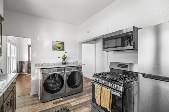 kitchen featuring light stone countertops, appliances with stainless steel finishes, separate washer and dryer, and dark hardwood / wood-style flooring