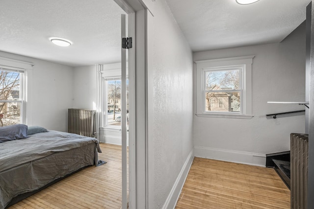 bedroom with multiple windows, a textured ceiling, and light wood-type flooring