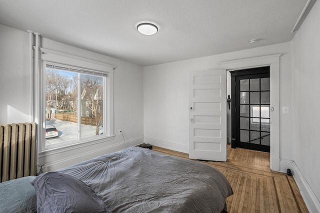 bedroom with radiator heating unit and hardwood / wood-style floors