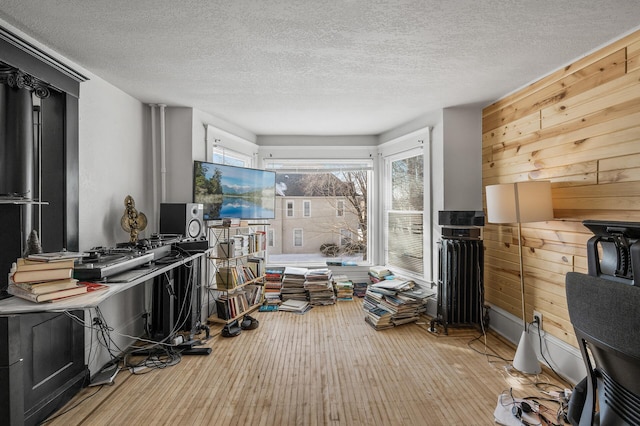 misc room featuring light hardwood / wood-style flooring, a textured ceiling, and wood walls