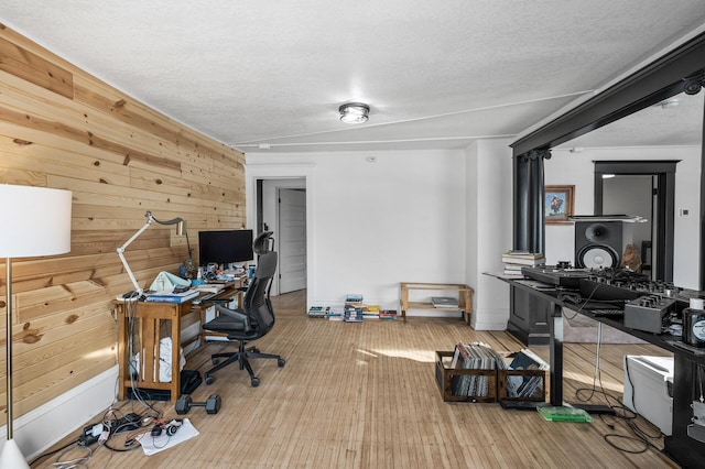 office area featuring hardwood / wood-style floors, wooden walls, and a textured ceiling