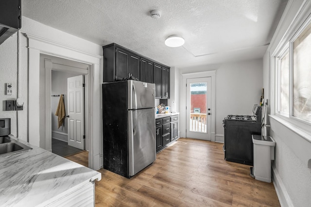 kitchen with range with gas cooktop, sink, stainless steel fridge, dark wood-type flooring, and a textured ceiling