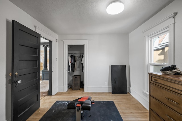 exercise area featuring a textured ceiling and light wood-type flooring