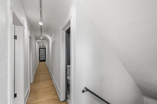 corridor featuring light hardwood / wood-style flooring and rail lighting