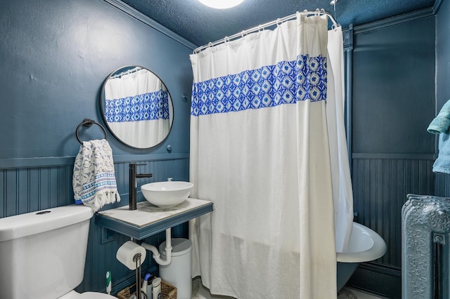 full bathroom with toilet, sink, a textured ceiling, ornamental molding, and shower / bathtub combination with curtain