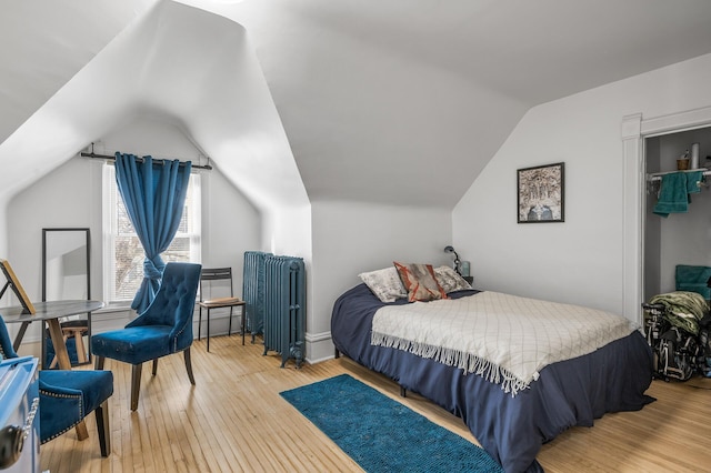 bedroom with hardwood / wood-style flooring, lofted ceiling, and radiator