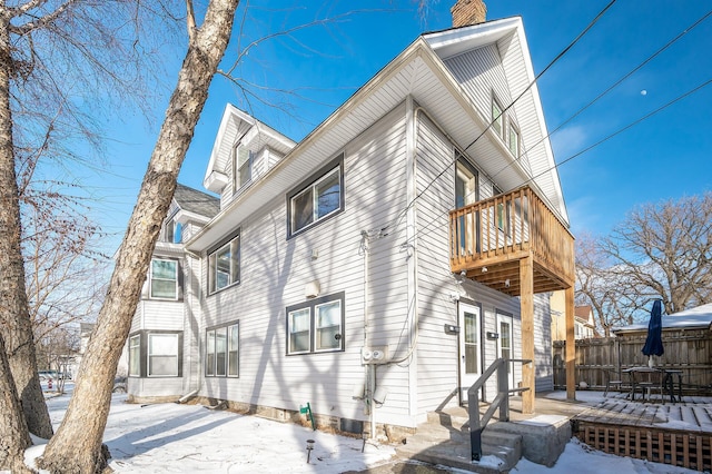 snow covered rear of property featuring a balcony and a deck