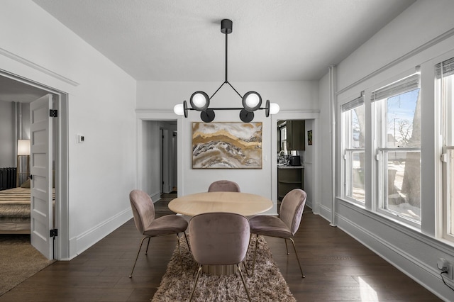 dining area with an inviting chandelier, dark hardwood / wood-style floors, and a textured ceiling