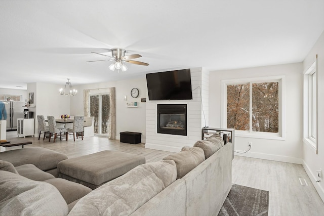 living area with ceiling fan, a fireplace, wood finished floors, and baseboards