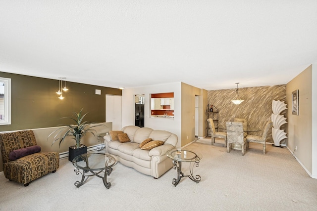 carpeted living room with an accent wall, a baseboard radiator, wooden walls, and baseboards