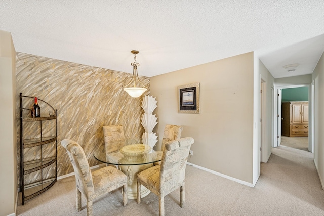 dining area featuring light colored carpet, an accent wall, wood walls, a textured ceiling, and baseboards