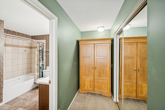 hall featuring light colored carpet, a textured ceiling, and baseboards