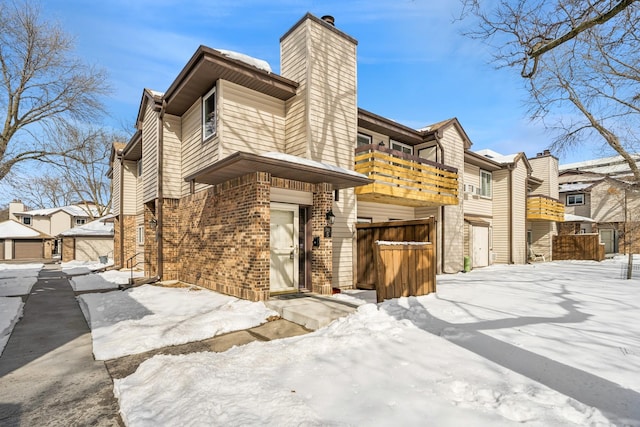 view of front of house with a balcony, a chimney, a residential view, and brick siding