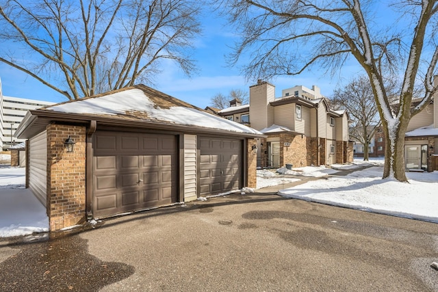 exterior space with a garage, an outbuilding, and brick siding