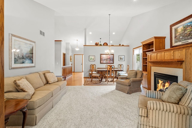 living room featuring an inviting chandelier, light colored carpet, and high vaulted ceiling