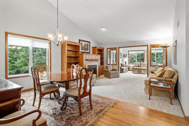 dining area with an inviting chandelier, hardwood / wood-style flooring, and high vaulted ceiling