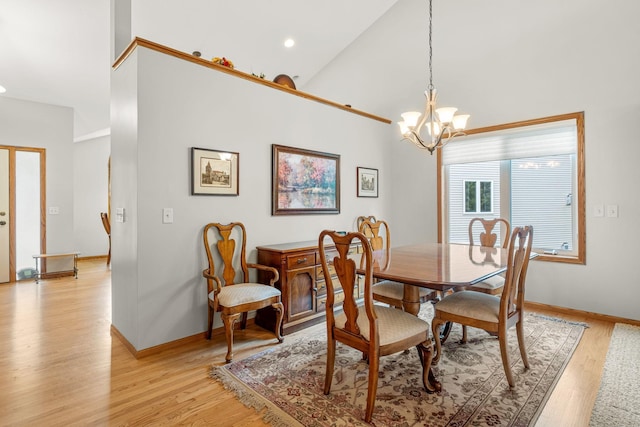 dining area featuring an inviting chandelier, high vaulted ceiling, and light hardwood / wood-style flooring