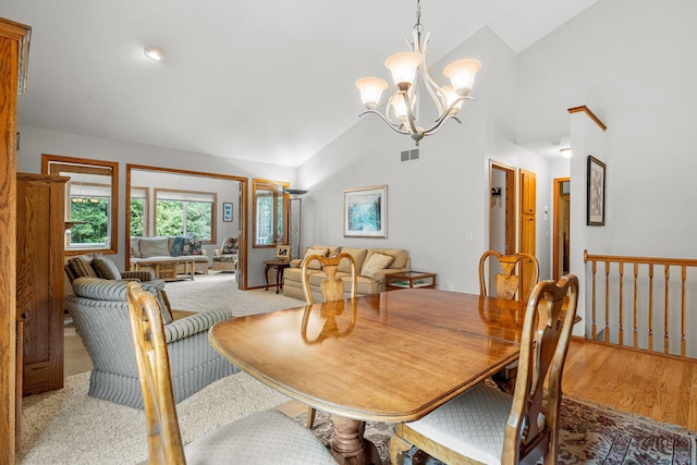 dining room with wood-type flooring, high vaulted ceiling, and an inviting chandelier