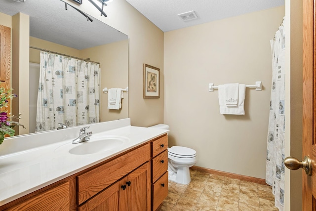 bathroom featuring vanity, a textured ceiling, and toilet