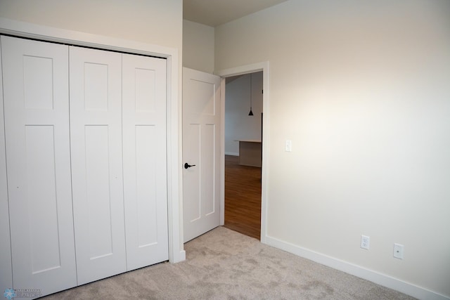 unfurnished bedroom featuring light carpet and a closet