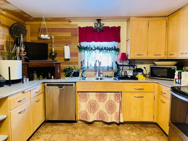 kitchen with light tile patterned flooring, stainless steel appliances, sink, and wood walls