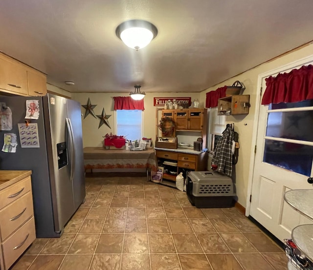 kitchen featuring stainless steel fridge with ice dispenser and dark tile patterned flooring