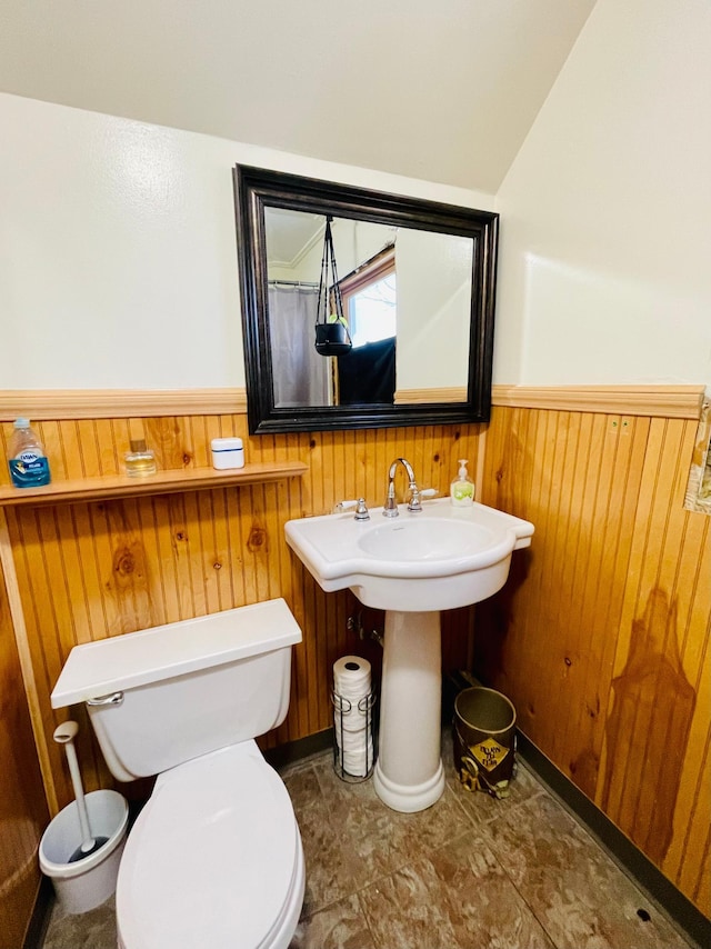 bathroom featuring wooden walls and toilet