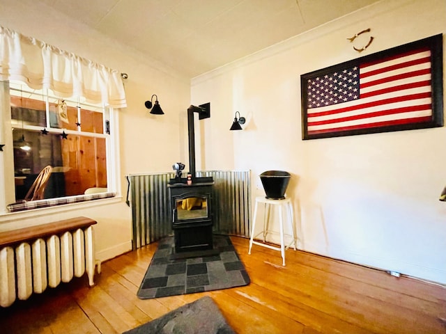 details with radiator, a wood stove, baseboards, and wood finished floors