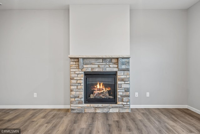 interior details with wood-type flooring and a stone fireplace