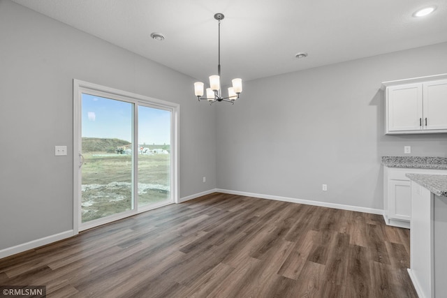 unfurnished dining area featuring a notable chandelier and dark wood-type flooring