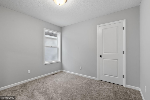 spare room featuring carpet floors and a textured ceiling