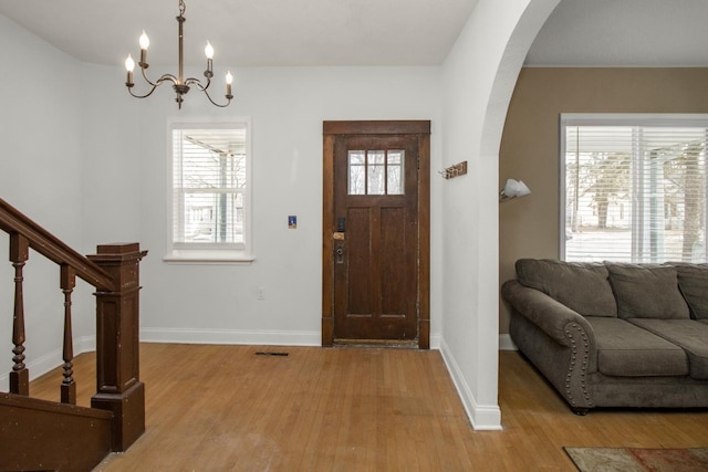 foyer featuring plenty of natural light, light wood-style flooring, and arched walkways