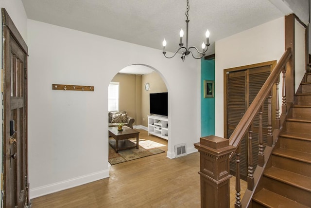 interior space featuring arched walkways, visible vents, baseboards, light wood-style floors, and stairway