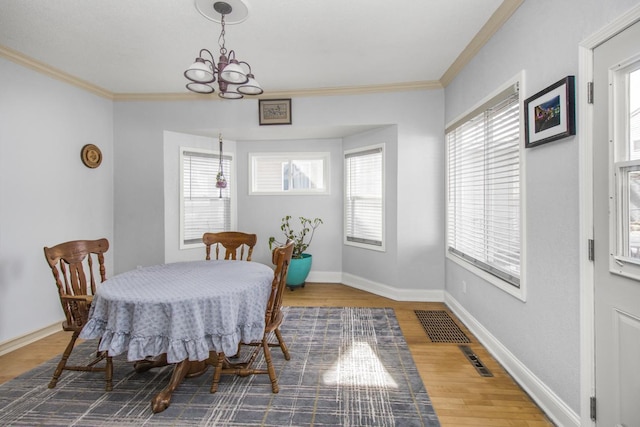 dining room with crown molding, a notable chandelier, visible vents, wood finished floors, and baseboards