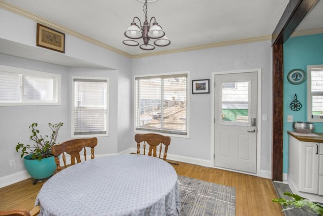 dining space with light wood-style floors, plenty of natural light, ornamental molding, and a chandelier