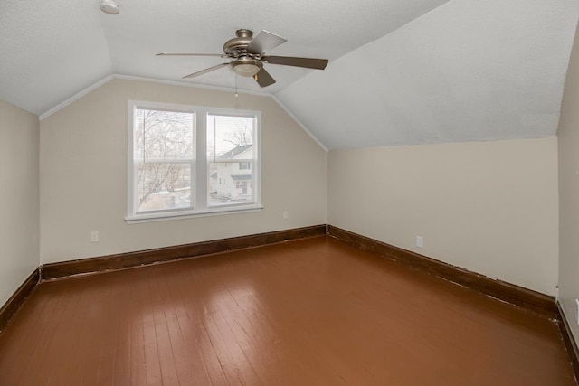 additional living space with ceiling fan, a textured ceiling, lofted ceiling, baseboards, and dark wood-style floors