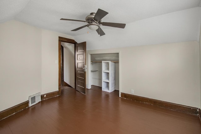 interior space with lofted ceiling, visible vents, a textured ceiling, and wood finished floors