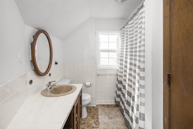 bathroom with tile walls, lofted ceiling, a shower with shower curtain, toilet, and vanity