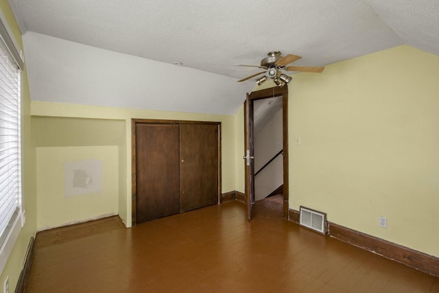 additional living space featuring lofted ceiling, a textured ceiling, wood finished floors, visible vents, and baseboards