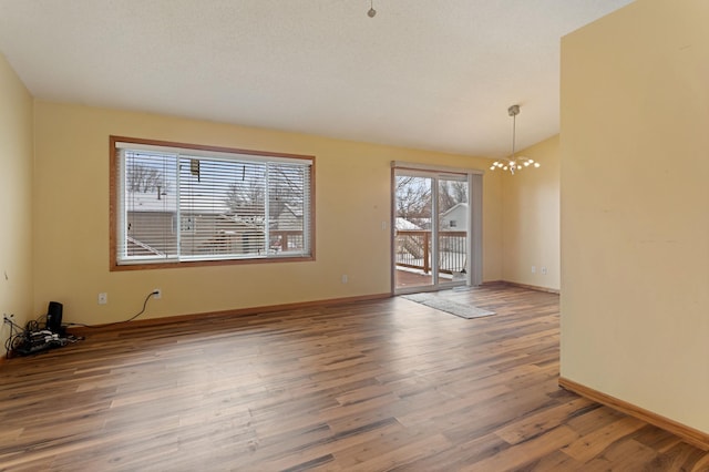 unfurnished room featuring wood-type flooring, a chandelier, and vaulted ceiling