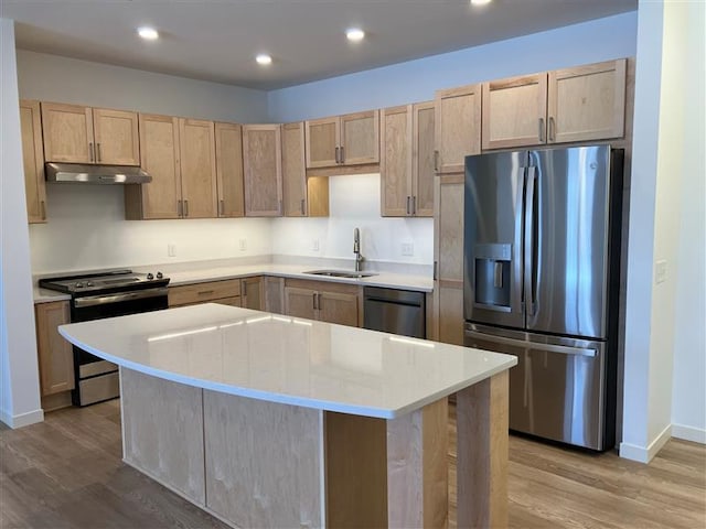 kitchen with stainless steel appliances, sink, a kitchen island, and light hardwood / wood-style flooring