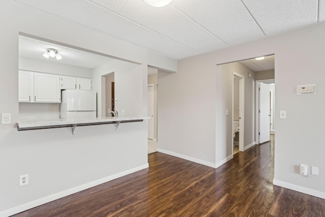 unfurnished living room featuring a sink, dark wood finished floors, and baseboards