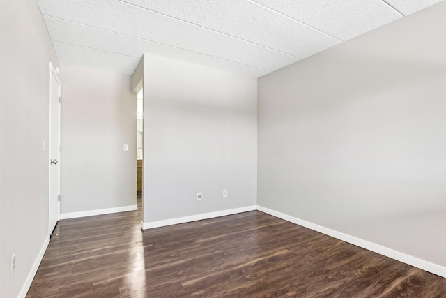 spare room featuring dark wood-style floors and baseboards