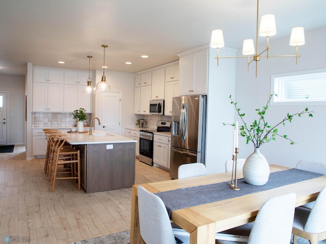 kitchen with pendant lighting, sink, stainless steel appliances, and white cabinets