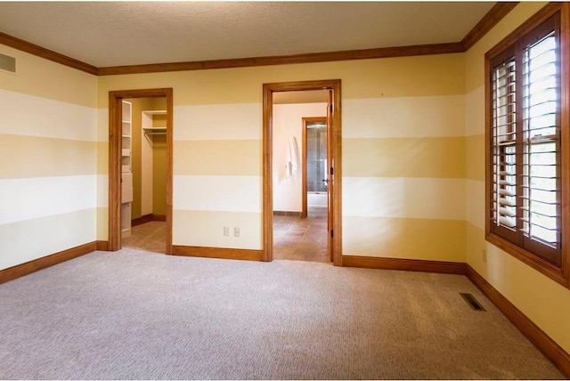 empty room featuring light carpet, ornamental molding, and a textured ceiling