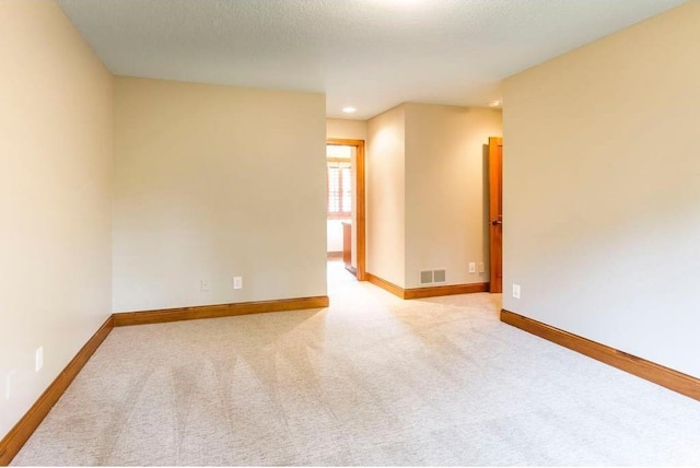 unfurnished room featuring light colored carpet and a textured ceiling