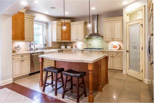 kitchen featuring pendant lighting, stainless steel appliances, a kitchen breakfast bar, a kitchen island, and wall chimney exhaust hood